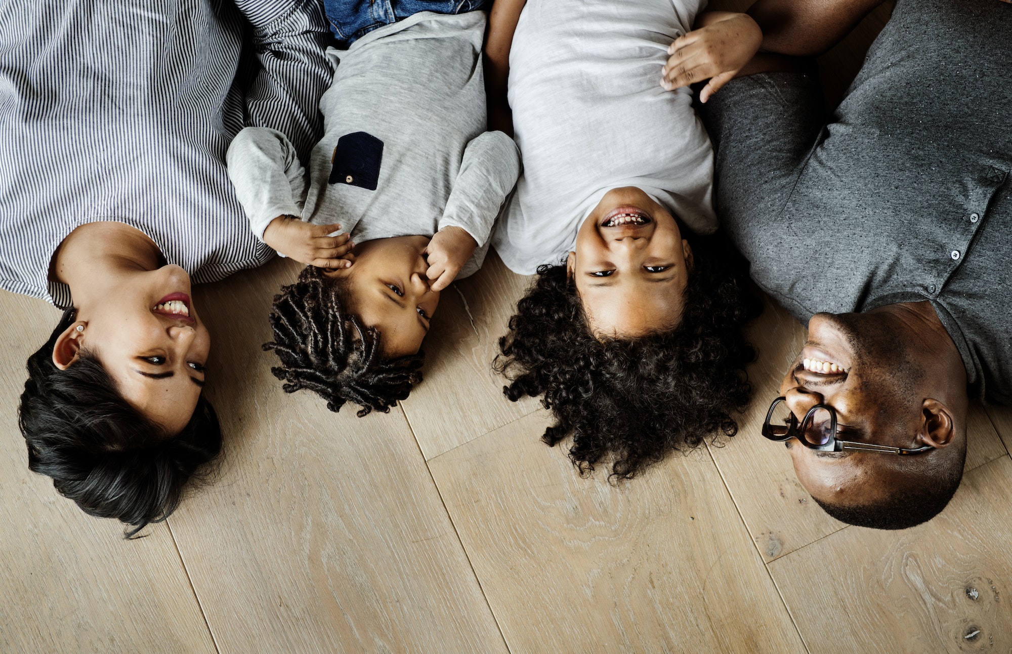 Asian-African family lying on wooden floor design space