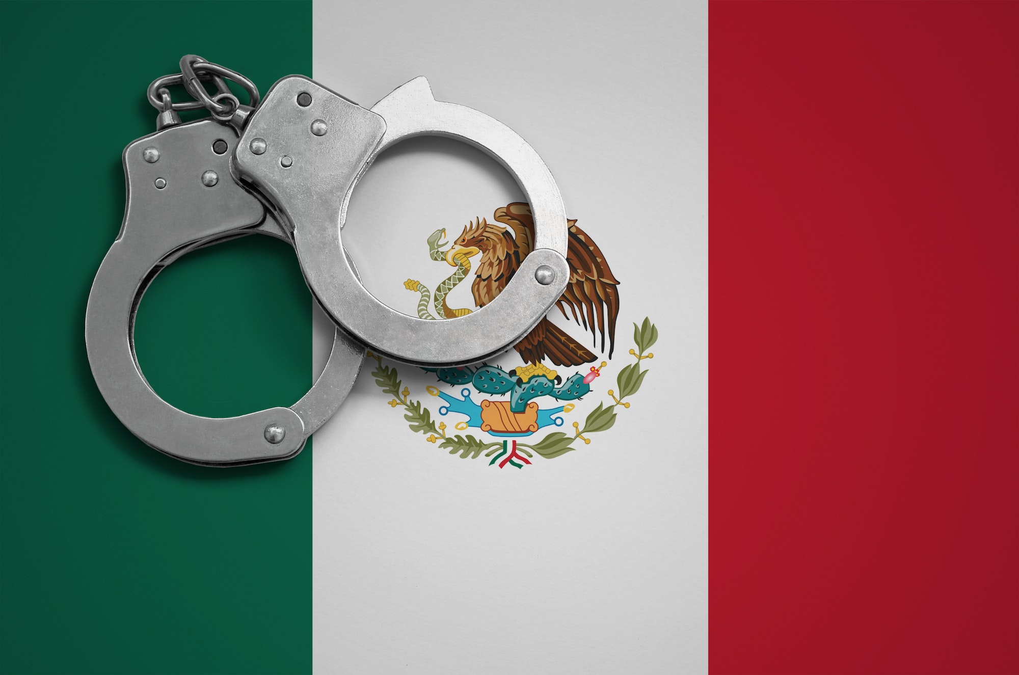 Mexico flag and police handcuffs. The concept of crime and offenses in the country.