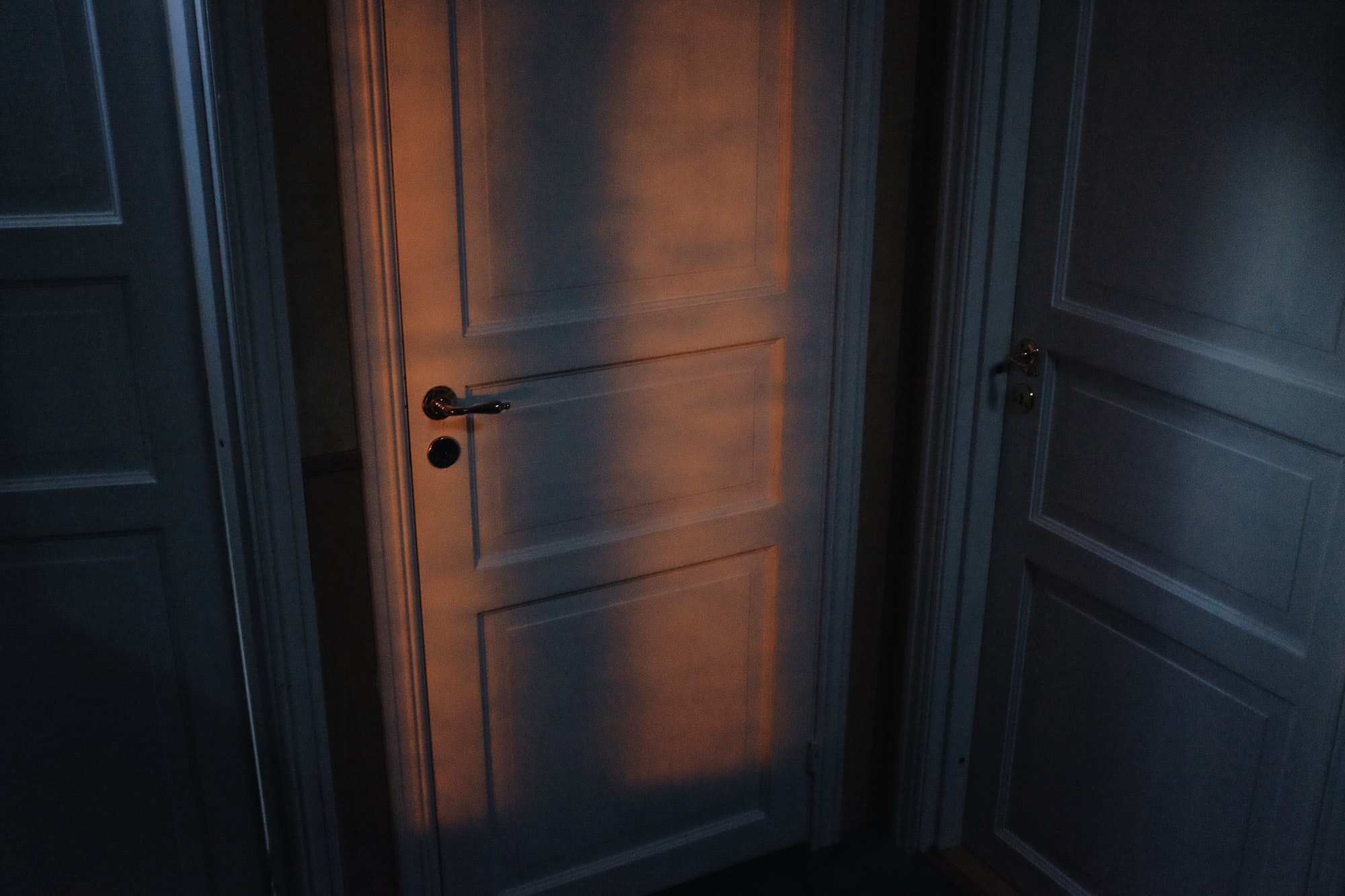 apartment hallway, three closed doors with atmospheric light at night, high grain